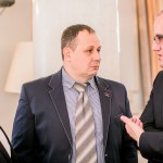 Trzej mężczyźni w garniturach podczas rozmowy w trakcie gali biznesowej.
